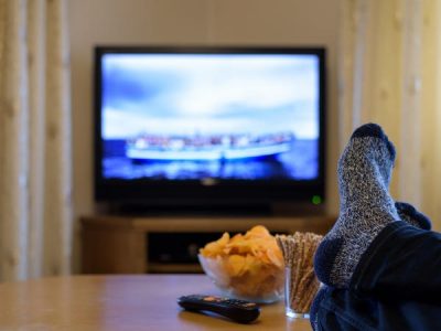 photo of person with feet up on table watching television