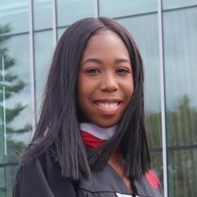 photo of woman smiling, wearing graduation gown